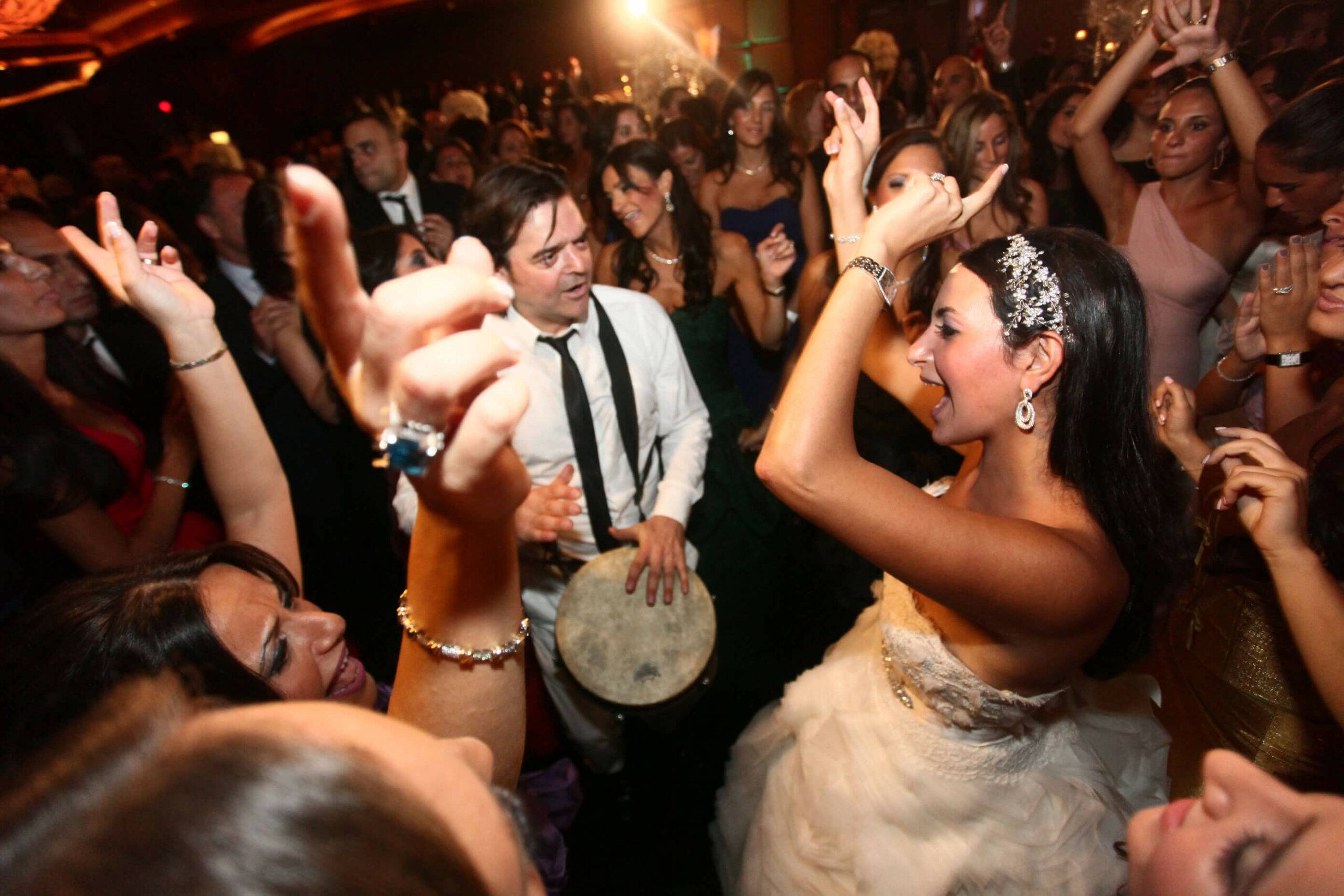 Jeunes mariés partageant un moment énergique, dansant autour d'un percussionniste passionné lors d'un mariage animé par SG Event, le DJ spécialisé à Nice.
